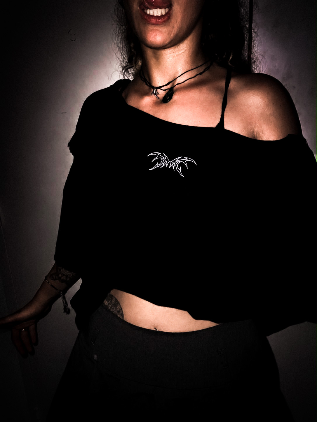 T-shirt recoupé à la main, col ouvert sur une épaule, logo ailes argenté